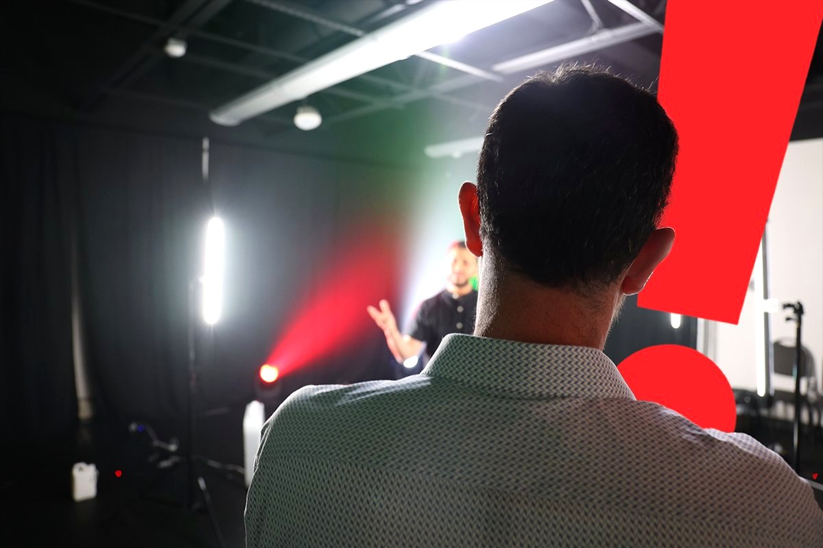 Idea Media crew lighting a studio set with red and white beams during a video shoot, with the brand's red exclamation mark in the frame